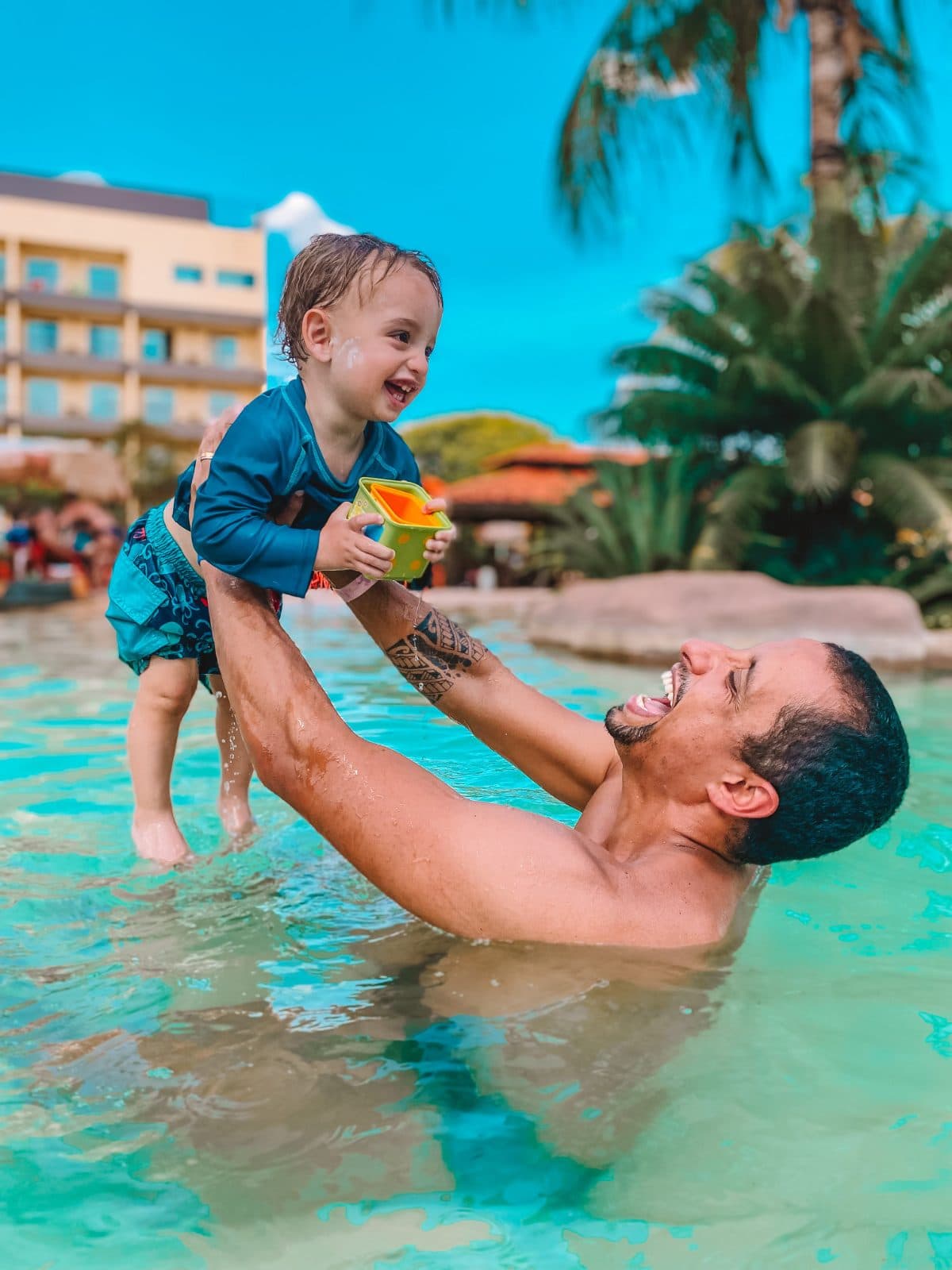 Pai brincando com o bebê na piscina do resort